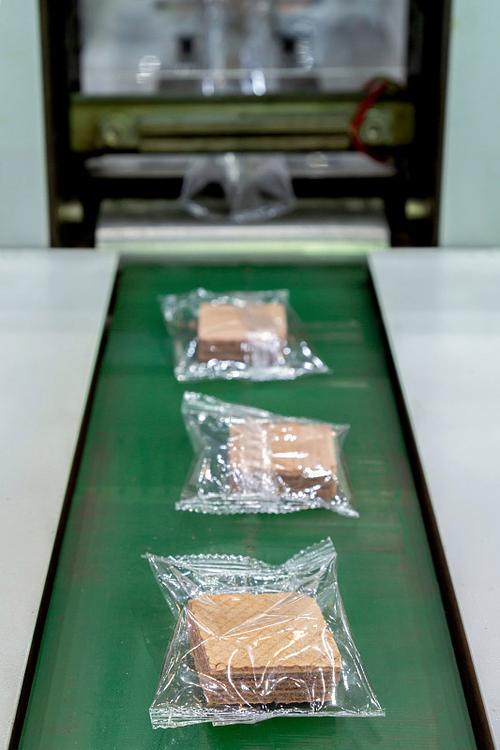 餅干的包裝在塑料背面在生產線上的自動包裝機的輸送帶在面包房工廠